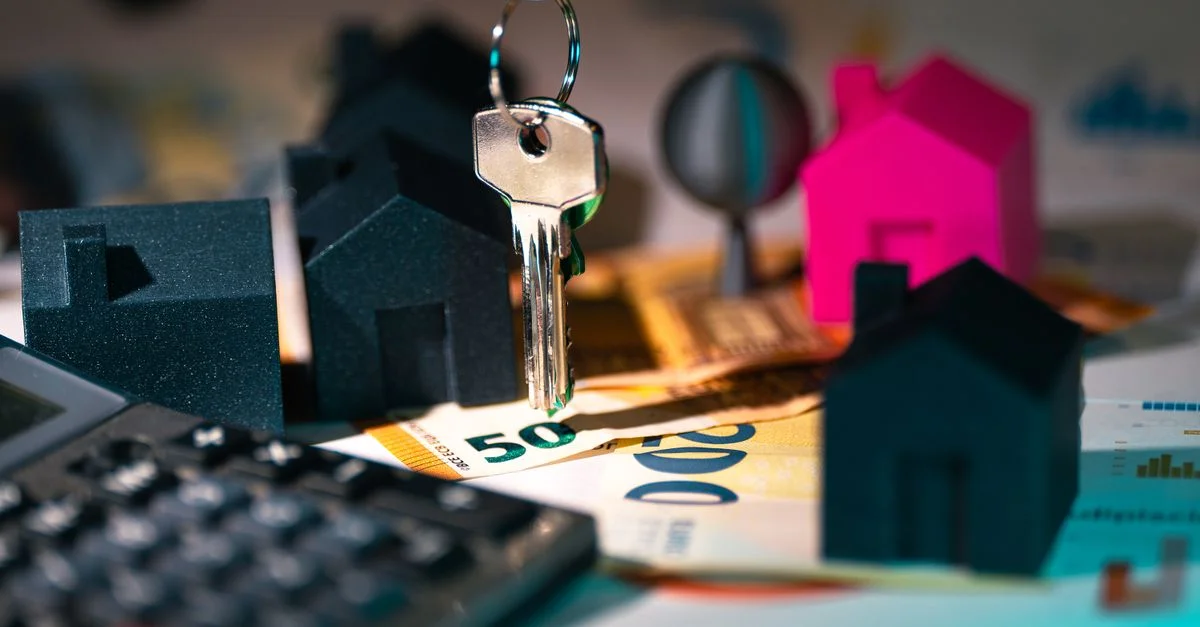 Une représentation symbolique des finances immobilières mettant en avant des clés, des maisons maquettes et des billets en euros.