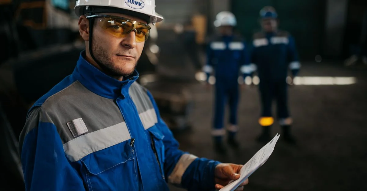 Un ouvrier industriel concentré, portant un équipement de protection, examine des documents dans une usine en Russie.