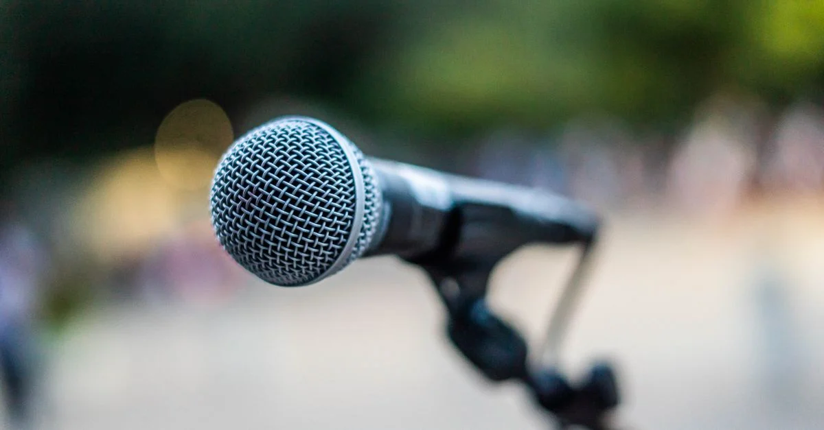 Un microphone sur un support capturé en extérieur avec un arrière-plan flou.