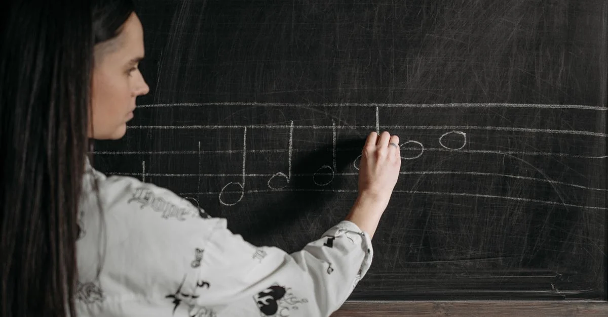 Une femme écrivant des notations musicales sur un tableau noir pendant un cours.