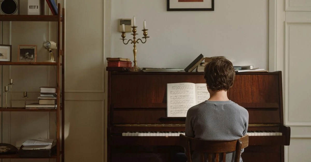 Adolescent assis devant un piano droit pratiquant de la musique dans une pièce cosy au style vintage.