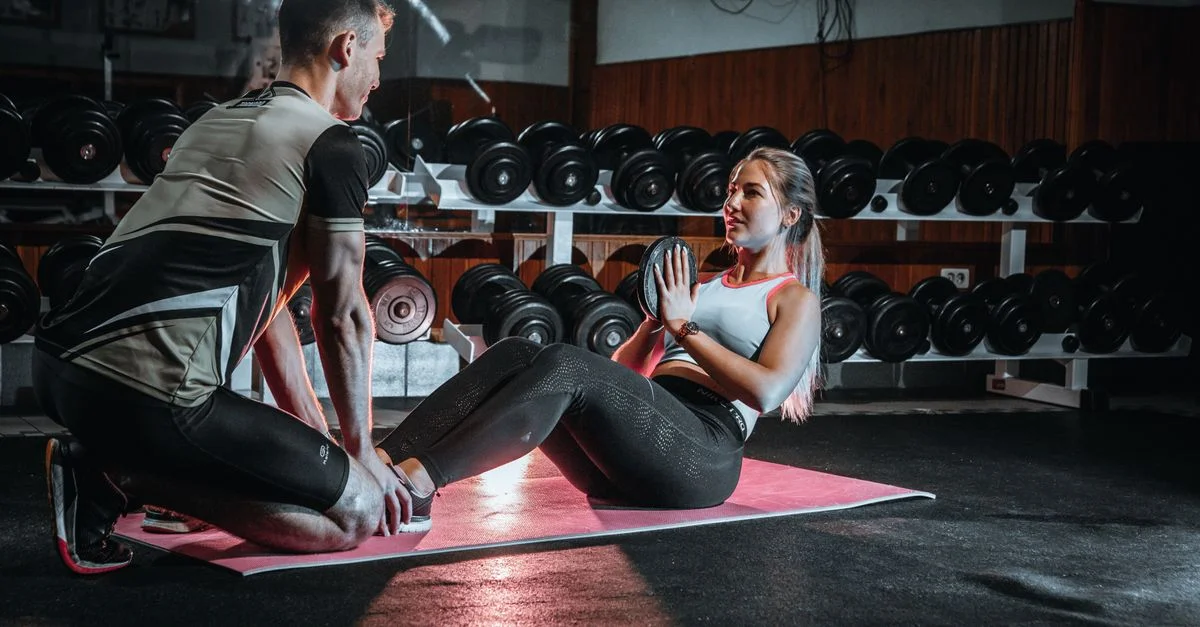 Homme et femme engagés dans une séance d'entraînement personnel dans une salle de sport, axés sur des exercices de base.