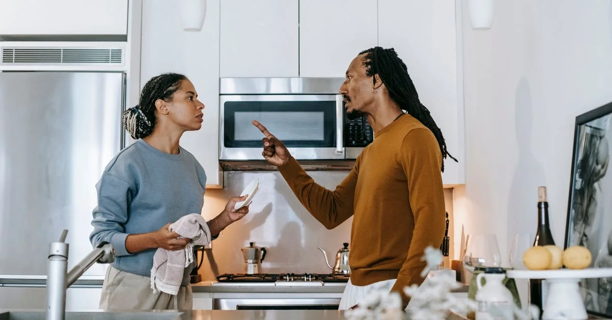 Un couple en pleine discussion animée dans une cuisine élégante, mettant en avant la dynamique de couple.