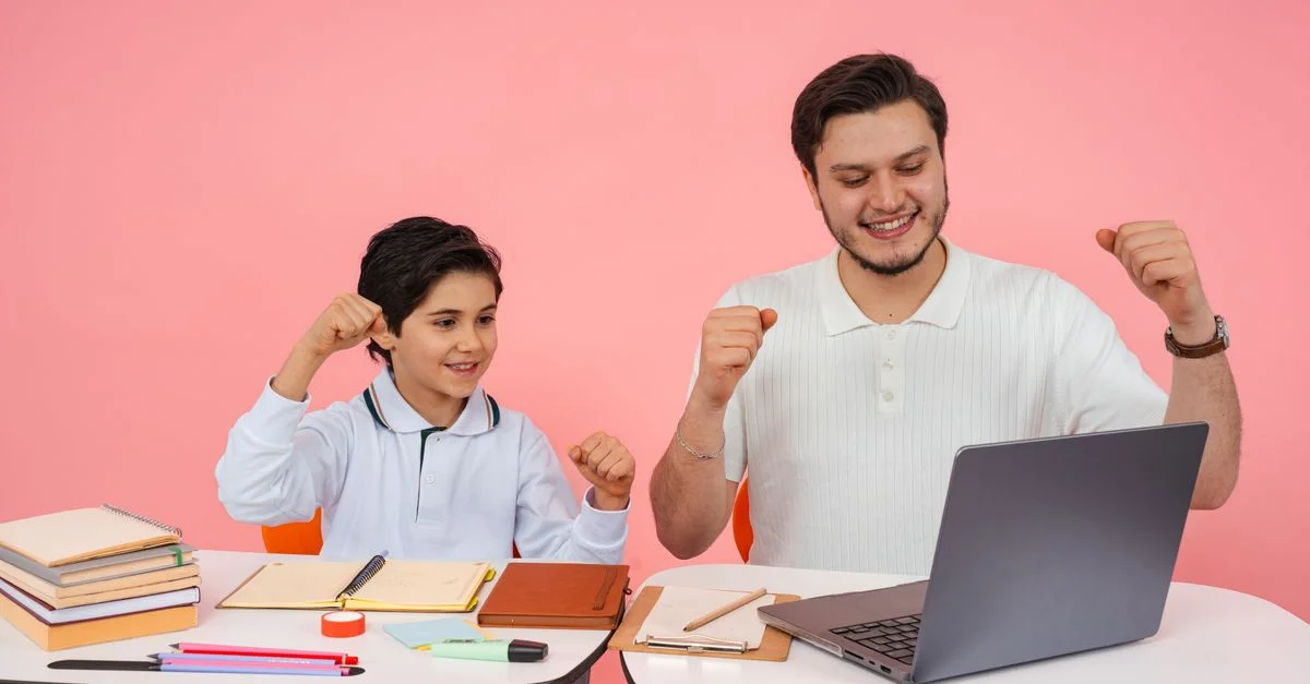 Un père et son fils célèbrent avec joie avoir terminé leurs devoirs ensemble sur un ordinateur portable.