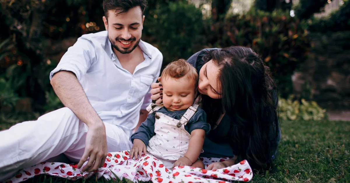 Une jeune famille profite d'un pique-nique ensoleillé avec son bébé dans un jardin.