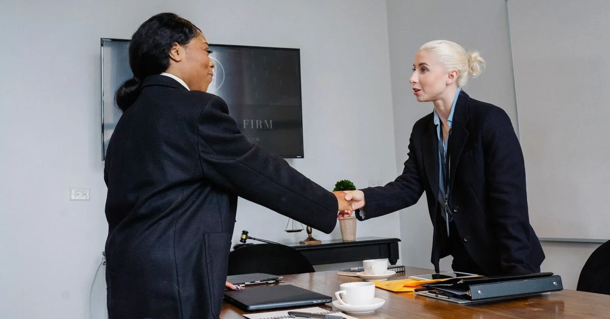 Deux femmes d'affaires se serrant la main dans un cadre de bureau, symbolisant le succès et la collaboration.